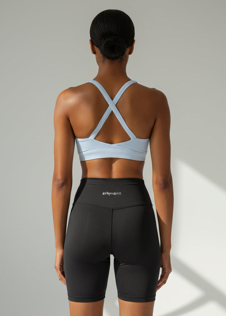 Woman wearing a light pale blue sports bra and black high-waisted shorts on a plain background. The ACTIVE CROP TOP is designed for runners who value freedom, comfort, and effortless performance.

Cross-over back straps follow the natural curve of your shoulder blades, allowing unrestricted arm movement and a natural feel through every stride. Lightweight and streamlined, this crop moves with you from warm-up to final sprint — so you can stay focused on the run.