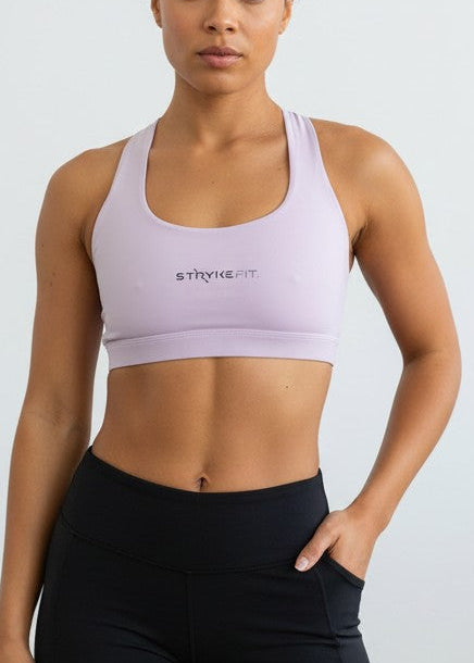 A woman modeling a light lavender sports bra and black athletic shorts against a plain white wall. The ATHLETE CROP TOP features a discrete back pocket, keeping your essentials close, whether it's your phone, gels, keys, or anything you need to go the distance without distractions.

The performance racerback design follows the natural line of your shoulders, allowing unrestricted movement and complete freedom through every stride. Engineered for support without compromising comfort