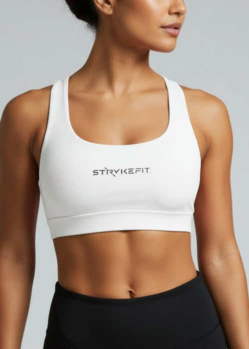 Woman wearing a white sports bra with 'STRYKE FIT' branding on a gray background. The ATHLETE CROP TOP is a new version of one of our most popular styles - Stryke Crop Top. This crop has a discreet back pocket to stash your phone, gels, or any running essentials.&nbsp;

The racerback design follows the natural line of your shoulders, unlocking full arm mobility while delivering uncompromising support. Lightweight, breathable, and made to move with you from the first step to the final sprint.