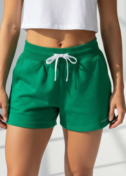 Woman wearing a white crop top and green shorts against a light background. The BALANCE FLEECE SHORT the perfect staple piece for your pre and post-training session. These shorts are a relaxed high waist fit with a rib elasticated waistband, drawstring, side pockets, and incredibly soft brushed fleece fabric.
DETAILS, Premium brushed fleece, Rib waistband with drawstring, Side pockets, Printed logo on left leg, Relaxed fit