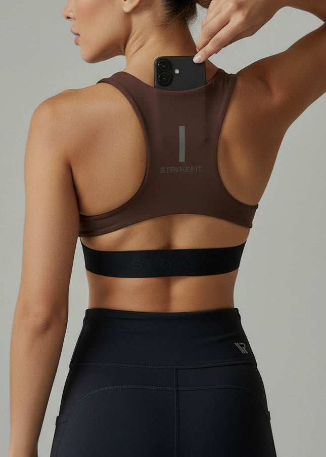 Woman wearing a brown sports bra and black shorts on a gray background. The FIT 2.0 CROP TOP is a new version of our most popular style, this crop has a discreet back pocket to stash your phone, gels, or any running essentials.&nbsp;

The racerback design follows the natural line of your shoulders, unlocking full arm mobility while delivering uncompromising support. Lightweight, breathable, and made to move with you from the first step to the final sprint.