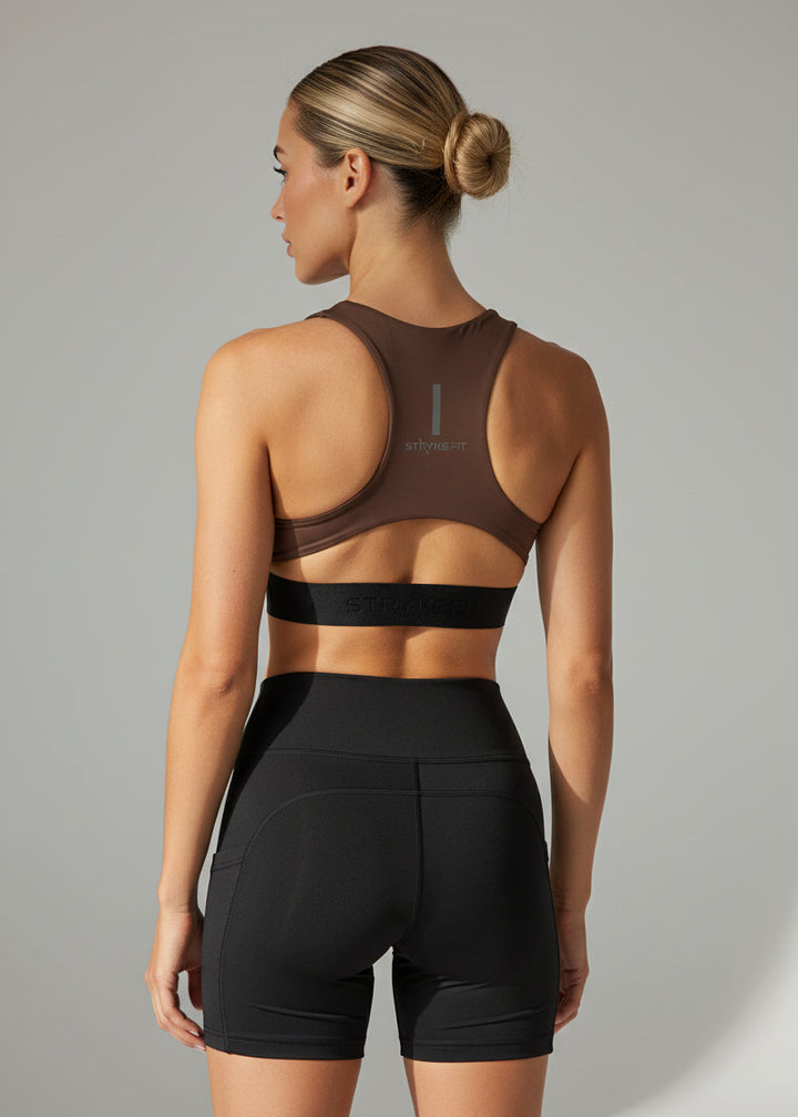 Woman wearing a brown sports bra and black shorts on a gray background. The FIT 2.0 CROP TOP is a new version of our most popular style, this crop has a discreet back pocket to stash your phone, gels, or any running essentials.&nbsp;

The racerback design follows the natural line of your shoulders, unlocking full arm mobility while delivering uncompromising support. Lightweight, breathable, and made to move with you from the first step to the final sprint.