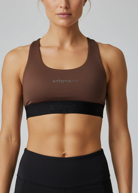 Woman wearing a brown sports bra and black shorts on a gray background. The FIT 2.0 CROP TOP is a new version of our most popular style, this crop has a discreet back pocket to stash your phone, gels, or any running essentials.&nbsp;

The racerback design follows the natural line of your shoulders, unlocking full arm mobility while delivering uncompromising support. Lightweight, breathable, and made to move with you from the first step to the final sprint.