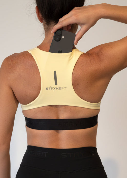 Woman wearing a light yellow sports bra and black shorts on a gray background.
The FIT 2.0 CROP TOP is a new version of our most popular style, this crop has a discreet back pocket to stash your phone, gels, or any running essentials.&nbsp;

The racerback design follows the natural line of your shoulders, unlocking full arm mobility while delivering uncompromising support. Lightweight, breathable, and made to move with you from the first step to the final sprint.